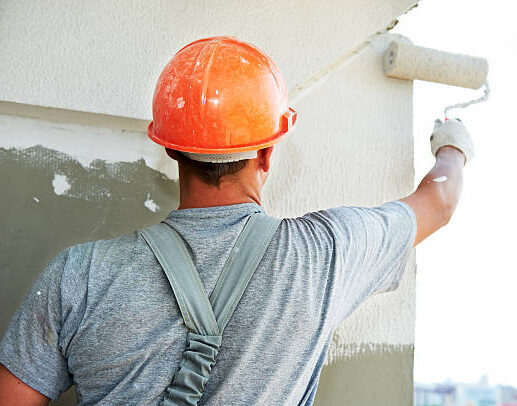 Young painting facade builder worker with roller at thermal insulation works Young painting facade builder worker with roller at thermal insulation works